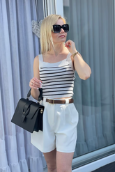 a lady in a square neck tank top and a pair of white shorts